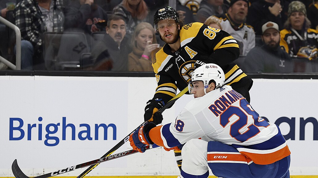 David Pastr�ák (naho�e) z Boston Bruins p�ihrává v zápase s New York Islanders...