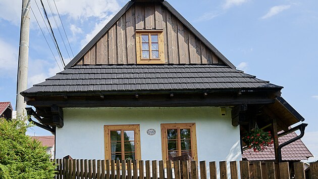 Fotogenická chalupa ve slovenské vsi Šumiac s tradiční střechou a ozdobným sloupkem.