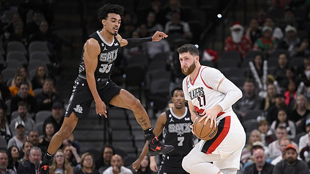 Tre Jones (vlevo) ze San Antonia vyskoil na fintu Jusufa Nurkie z Portlandu.