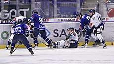 Hokejisté Vítkovic v bílých dresech a Plzn v modrých bojují o puk u manitnelu.