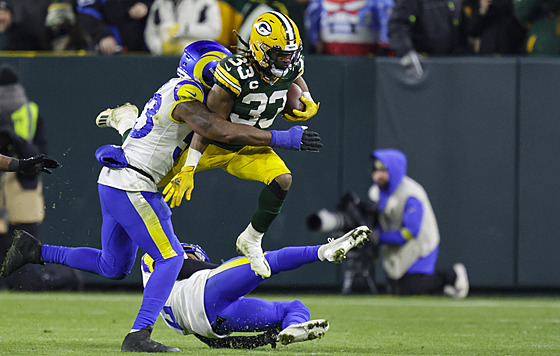 Aaron Jones (s míem) z Green Bay Packers v souboji s Troyem Hillem (na zemi) a...