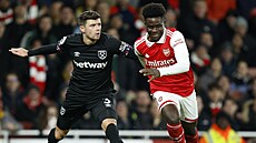 Bukayo Saka (vpravo) z Arsenalu s úsmvem obchází Aarona Cresswella z West Hamu.