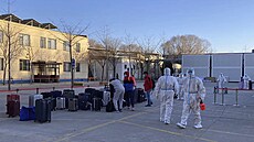 Pracovníci v ochranných od�vech p�ijímají cestující z letadla p�ilétajícího ze...