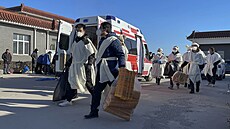 Rodinní p�íslu�níci nosí pytle s papírovými ob�mi pro svého zesnulého...