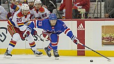 Obránce New Yorku Rangers Adam Fox se natahuje po kotoui ped napadajícím...