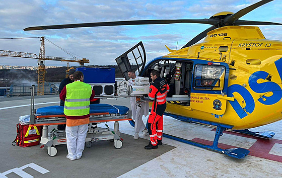 Lékai a záchranái vyndávají inkubátor na heliportu nemocnice v praském...