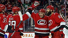 Martin Neas, Paul Stastny a Brent Burns (zleva) slaví gól Carolina Hurricanes.
