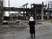 Žena stojí před zničenou chemičkou v ruském městě Šebekino nedaleko hranic s...