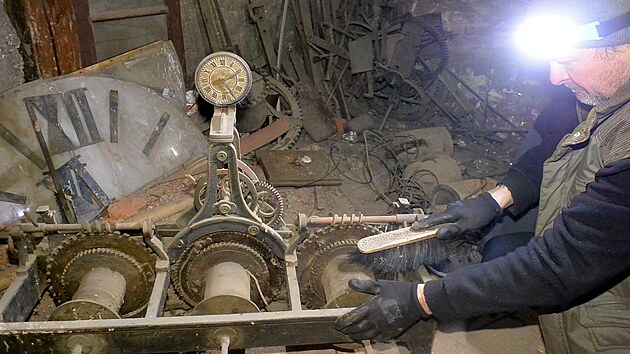 Hodinář Jan Kopřiva čistí starý hodinový stroj, který vyrobila před více než 100 lety firma Rudolf Thöndel z Uničova. V pozadí je vidět mnohem starší kovaný  stroj z 18. století.
