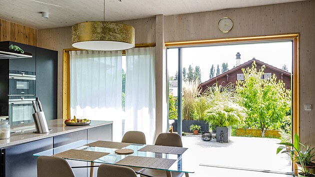 Jedním z důvodů, proč obývací prostor s kuchyní působí vzdušně, je propojení s útulnou terasou obklopenou rostlinami.