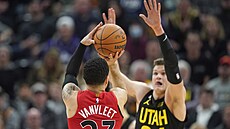 Fred VanVleet (zády) z Toronta stílí pes bránícího  Walkera Kesslera z Utahu.