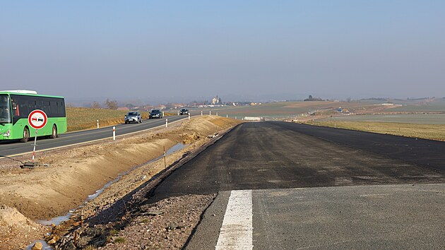 Konec st�vaj�c� silnice a nov� ��sti s ji� polo�enou vrstvou asfaltu.