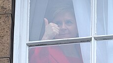 Nicola Sturgeonová ukazuje palec nahoru z okna Bute House poté, co v Edinburghu...