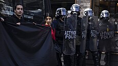 Univerzitní studenti drží černé sukno a stojí vedle policistů, kteří brání...