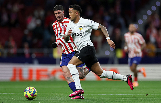 Útočník Justin Kluivert z Valencie vede míč před Rodrigem de Paulem z Atlétika.