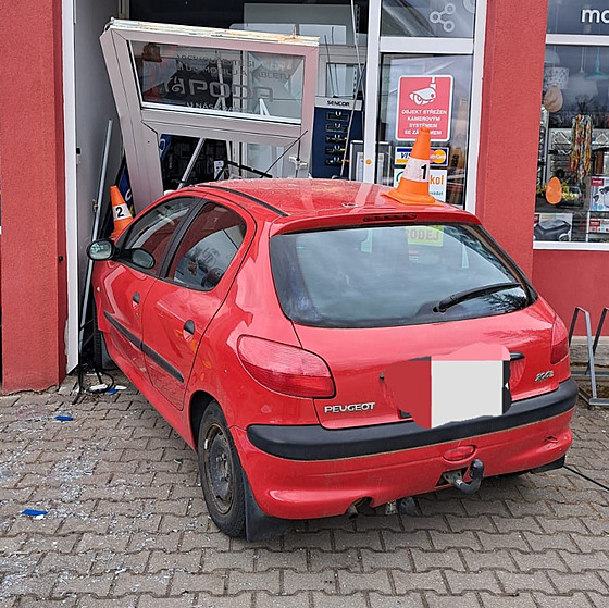 Senior vjel s vozem znaky Peugeot do výlohy obchodu.