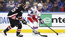 Útoník New York Rangers Patrick Kane (vpravo) vede puk, ze strany ho stíhá...