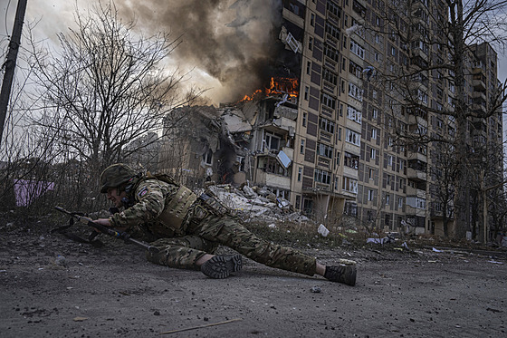 Ukrajinský policista se schovává ped hoící budovou, která byla zasaena pi...