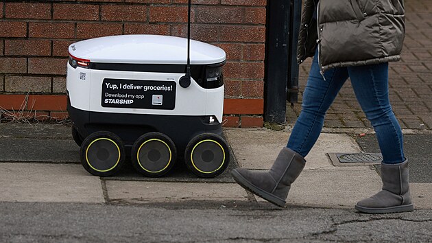 Lid prochzej kolem doruovacho robota v Sale v Britnii (21. bezna 2023)