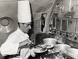 Na snímku z roku 1949 éfkucha servíruje jídlo na talí v kuchyni letadla...