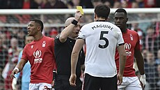 Rozhodí Simon Hooper ukazuje lutou kartu obránci Manchesteru United Harrymu...