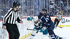 Adam Ra�ka (57) ze San Jose Sharks schytává u mantinelu ránu od Joshe...