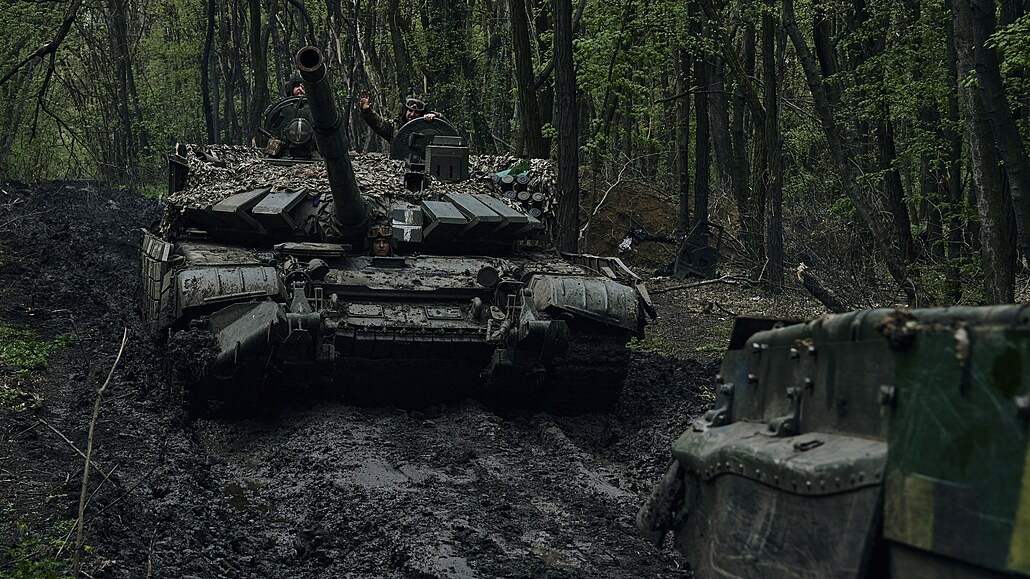 Ukrajinští vojáci mávají na projíždějícím tanku na frontové linii u Bachmutu....