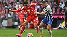 Zálo�ník Bayernu Mnichov Jamal Musiala v souboji s obráncem Herthy Berlín...