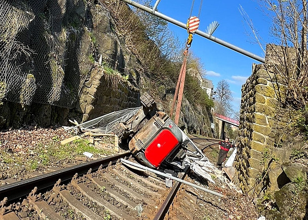 Bagr spadl z korby náklaďáku do kolejiště, řidič si najel příliš blízko srázu