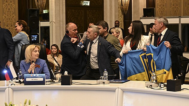 lenov ukrajinsk delegace rozvjej svou sttn vlajku vedle Olgy Timofejevov, zstupkyn vedouc rusk delegace, aby naruili jej projev bhem zasedn Parlamentnho shromdn ernomosk hospodsk spoluprce (PABSEC) v tureck Ankae. (4. kvtna 2023)