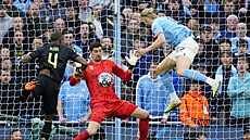 Erling Haaland z Manchesteru City (vpravo) hlavikuje na bránu Thibauta...