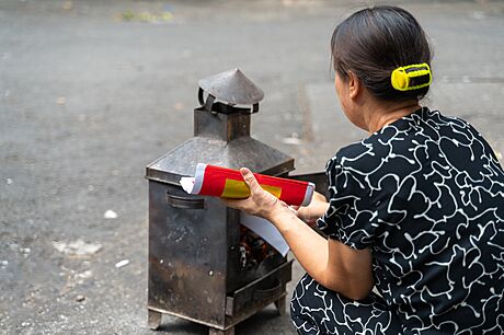 Vietnamská seniorka pálí peníze na hanojské ulici. Ví se, e akt pálení...