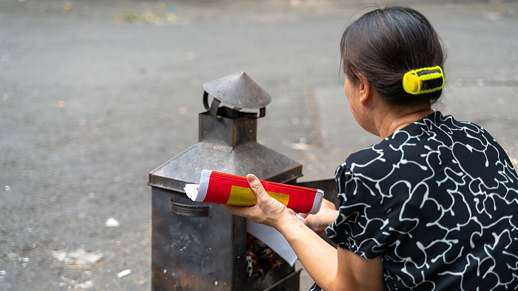 Vietnamská seniorka pálí peníze na hanojské ulici. Ví se, e akt pálení...