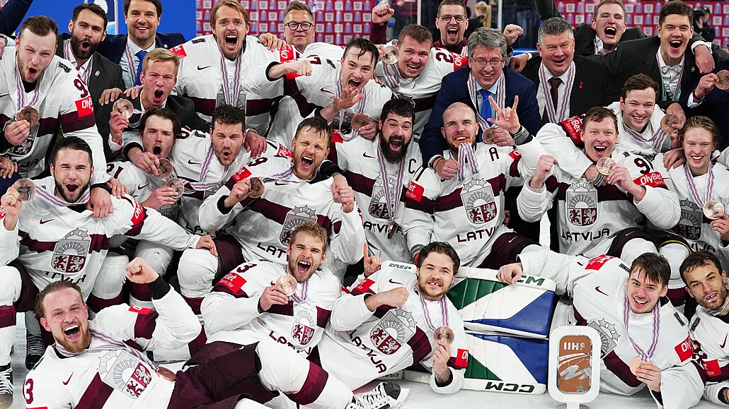Lotyšští hokejisté si dávají týmové foto s bronzovými medailemi.