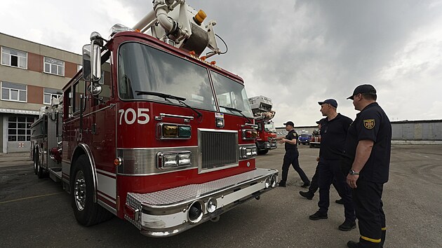 Ukrajinští hasiči si prohlížejí americký hasičský vůz, dar hasičského sboru z Bedfordu z Illinois.  Hasičské sbory různých států USA nabídly pro válkou postižený východ Ukrajiny 18 hasičských vozů plně vybavených záchranářskou technikou (25. května 2023)