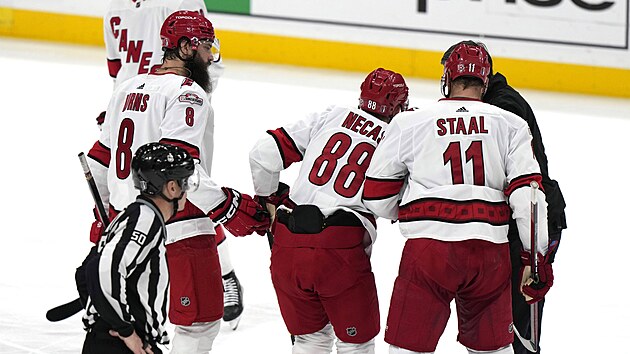 Martin Neas (88) z Carolina Hurricanes sw tce zved z ledu, pomhaj mu Brent Burns (8) a Jordan Staal (11).