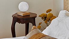 Levitující lampu si majitelka umístila na starožitný stolek vedle postele.