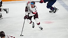 Lotyský útoník Miks Indrais (70) manévruje s pukem v utkání o bronz na...