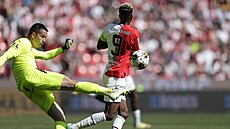 Branká� Slovácka Filip Nguyen odkopává mí� p�ed slávistickým Peterem Olayinkou.