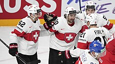 �výcarský úto�ník Andres Ambuhl (10) oslavuje v objetí spoluhrá�� gól proti...