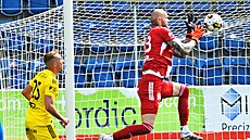 Olomoucký branká� Matú� Macík jde po mí�i, zákroku p�ihlí�í spoluhrá� Denis...