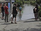 Místní obyvatelé hovoí u svých dom zaplavených vodou poté, co ruská vojska v...