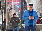 Mui hledí do svých telefon ped náborovým billboardem v Petrohrad. (12....