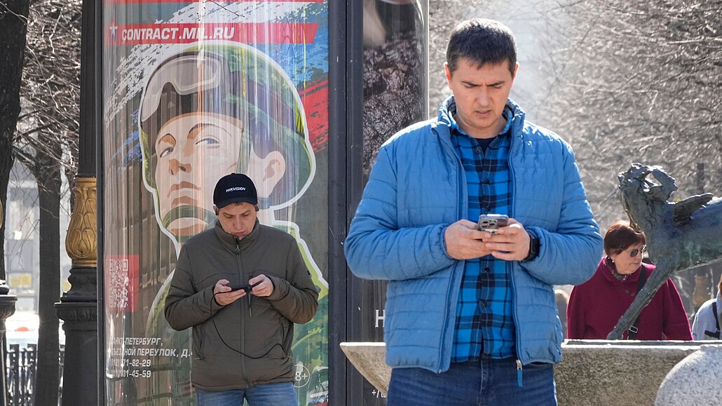 Mui hledí do svých telefon ped náborovým billboardem v Petrohrad. (12....