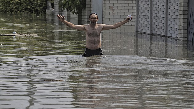 Místní obyvatel gestikuluje u svého domu, který byl zaplaven vodou z přehrady Kachovka. (6. června 2023)