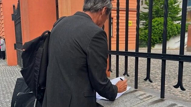 Martin Stropnick podepisuje ped budovou soudu na zdce u plotu Justinho palce v Praze Na Mnkch dohodu o rozvodu a vivnm (8. ervna 2023).