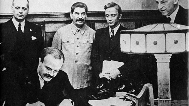 Vja�eslav Molotov podepisuje, von Ribbentrop a Stalin p�ihl�ej�.