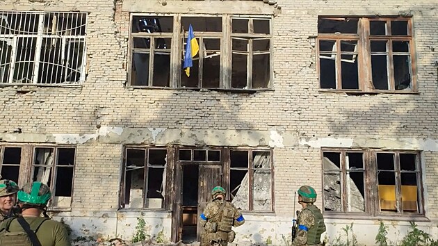 Ukrajint vojci stoj ped svou vlajkou bhem operace, na jejm zklad bylo oficiln potvrzeno osvobozen prvn vesnice v rmci letn protiofenzivy. Tou obc je Blahodatne v Donck oblasti. (11. ervna 2023)