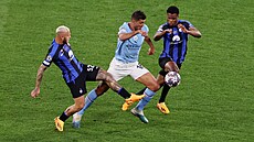 Záloník Rodri z Manchesteru City proniká mezi dvma hrái Interu Milán.