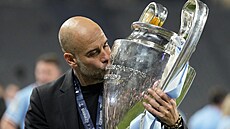 �pan�lský trenér fotbalového Manchesteru City Pep Guardiola se laská s trofejí...